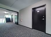 Thumbnail 12 of 44 - A hallway with a black door and a red fire extinguisher on the wall. at Highland Club Apartments, Watervliet, NY 12189