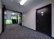 Thumbnail 10 of 44 - an empty hallway with a black door and a staircase at Highland Club apartments, Watervliet, NY 12189