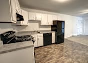Thumbnail 7 of 21 - A kitchen with black and white appliances and wooden floors.