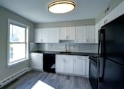 Thumbnail 2 of 47 - A kitchen with black appliances and white cabinets.