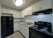 Thumbnail 5 of 30 - A kitchen with black appliances and white cabinets.