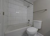 Thumbnail 11 of 30 - A white toilet sits next to a bathtub in a bathroom.