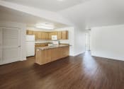 Thumbnail 4 of 33 - an empty living room and kitchen with wood floors and white walls