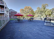 Thumbnail 34 of 38 - A park area with a bench and a table with a red umbrella.