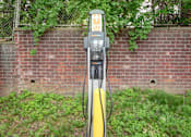 Thumbnail 39 of 41 - A yellow and black electric vehicle charging station sits in front of a brick wall.