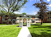 Thumbnail 16 of 29 - A small white gazebo is in the middle of a grassy area in front of apartment buildings.