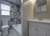 Thumbnail 10 of 25 - A white toilet sits next to a white bathtub in a bathroom.