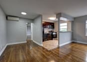 Thumbnail 12 of 25 - A room with wooden floors and a kitchen area in the background.