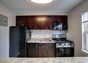 Thumbnail 6 of 25 - A kitchen with black appliances and brown cabinets.