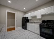 Thumbnail 5 of 27 - A kitchen with black appliances and white cabinets at Willett Apartments, Albany, New York