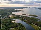 Thumbnail 1 of 2 - An aerial view of a river flowing through a forested area with a cloudy sky above.