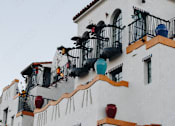 Thumbnail 17 of 30 - A white building with balconies and plants.