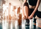 Thumbnail 10 of 30 - A person tying their shoelaces in a gym.