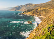 Thumbnail 11 of 30 - A coastal landscape with waves crashing against the shore.