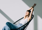 Thumbnail 7 of 30 - A woman is sitting in a chair with her arms raised.
