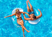 Thumbnail 20 of 20 - A man and a woman are floating on separate inner tubes in a swimming pool.