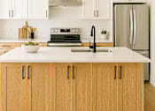 Thumbnail 11 of 14 - A modern kitchen with wooden cabinets and a white countertop.