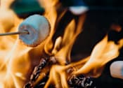 Thumbnail 4 of 7 - A marshmallow is being roasted over an open flame.