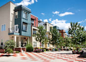 Thumbnail 10 of 17 - A modern building with a green and white facade is surrounded by a courtyard with a red and white checkered floor.