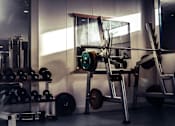 Thumbnail 5 of 5 - A gym with a weight bench, dumbbells, and a barbell.