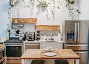 Thumbnail 14 of 14 - A kitchen with a wooden table and stainless steel appliances.