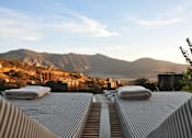 Thumbnail 8 of 13 - A mountain range is in the background of a building with a striped roof.