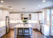 Thumbnail 2 of 8 - A kitchen with white cabinets and a large island.