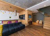 Thumbnail 1 of 8 - A living room with a blue couch and wooden stairs.