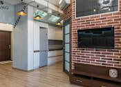 Thumbnail 4 of 5 - A modern living room with a brick fireplace and a flat screen TV.