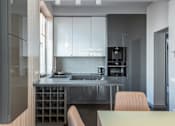 Thumbnail 3 of 5 - A modern kitchen with a dining table and chairs.