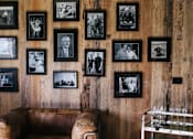 Thumbnail 5 of 6 - a leather couch sits in front of a wall of black and white photos