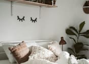 Thumbnail 2 of 5 - A cozy bedroom with a bed, pillows, a book, and plants.