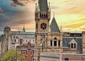 Thumbnail 6 of 8 - A church steeple rises above a row of buildings in a city.
