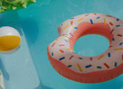 Thumbnail 1 of 5 - A pineapple and a donut float in a pool.
