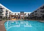 Thumbnail 15 of 16 - A swimming pool in front of apartment buildings.