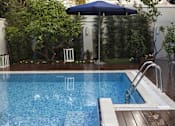 Thumbnail 4 of 5 - a swimming pool with a blue umbrella and trees in the background
