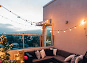 Thumbnail 6 of 12 - a roof terrace with a sectional sofa and string lights