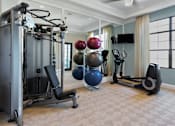 Thumbnail 9 of 11 - A home gym with a variety of equipment including a leg press machine, a rowing machine, and a bench press.