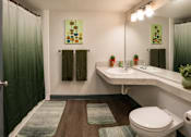 Thumbnail 9 of 10 - A bathroom with a toilet, sink, and shower curtain.