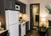Thumbnail 8 of 10 - A kitchen with a white fridge and a black chair.