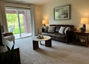 Thumbnail 13 of 41 - A living room with a couch, coffee table, and sliding glass doors.