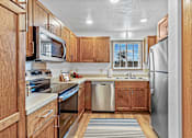 Thumbnail 1 of 12 - A kitchen with wooden cabinets and stainless steel appliances.