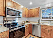 Thumbnail 2 of 12 - A kitchen with wooden cabinets and stainless steel appliances.