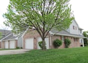 Thumbnail 10 of 12 - A tree in front of a house with a grey roof.