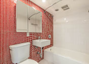 Thumbnail 37 of 47 - A red tiled bathroom with a white toilet, sink, and bathtub.