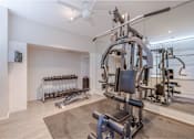 Thumbnail 26 of 47 - A home gym with a variety of equipment including a weight bench, dumbbells, and a cable machine.