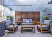 Thumbnail 21 of 47 - A patio with wooden furniture and a grey cushion.