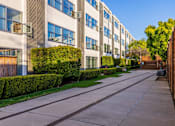 Thumbnail 22 of 47 - A long concrete walkway leads between two rows of apartment buildings.