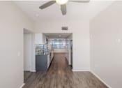 Thumbnail 43 of 47 - A spacious room with a ceiling fan and a kitchen area in the background.