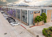 Thumbnail 35 of 47 - A parking lot with a white car parked in front of a building that has a sign that says "Now Leasing".